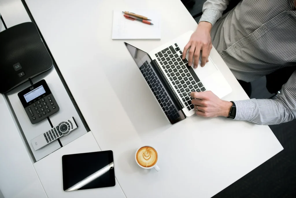 Overhead view of someone working on a laptop at a desk with a coffee