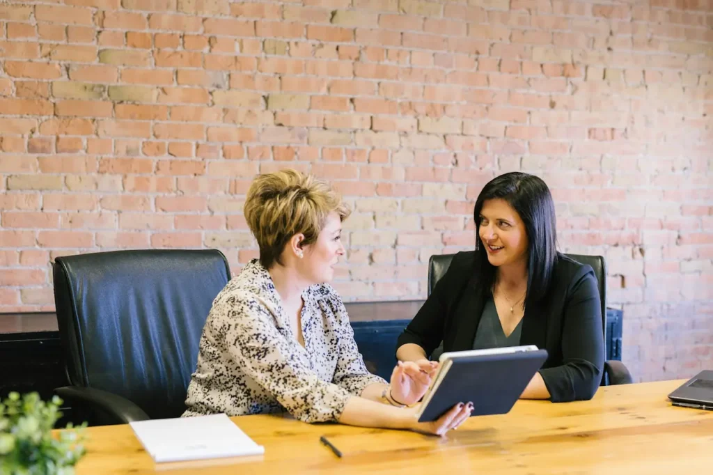 Two colleagues discussing payroll on a tablet in an office meeting room